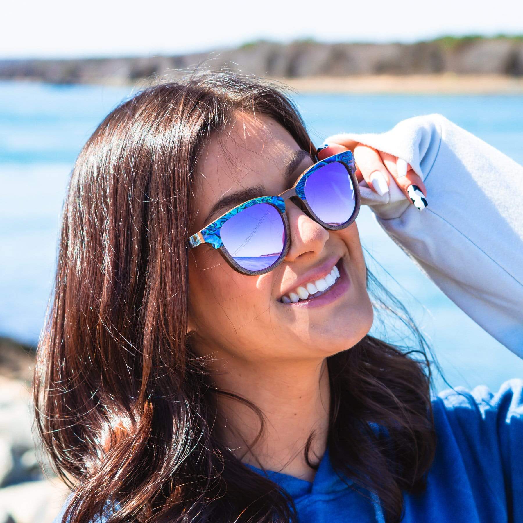 Model Wearing Wooden Beachcomber Abalone Seashell Sunglasses With Violet Lenses At The Beach
