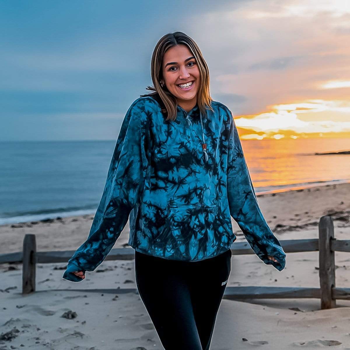Female Model At The Beach Wearing A Blue Smoke Cloud Blend Hoodie From SLYK