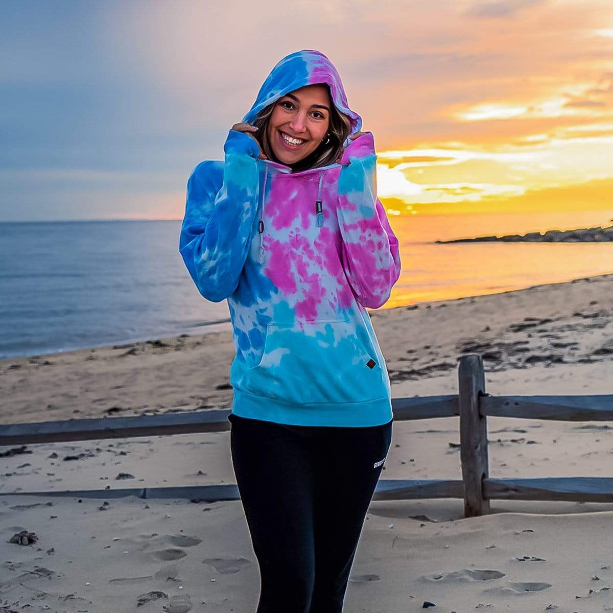 Female Model At The Beach Wearing A Cotton Candy Cloud Blend Hoodie From SLYK