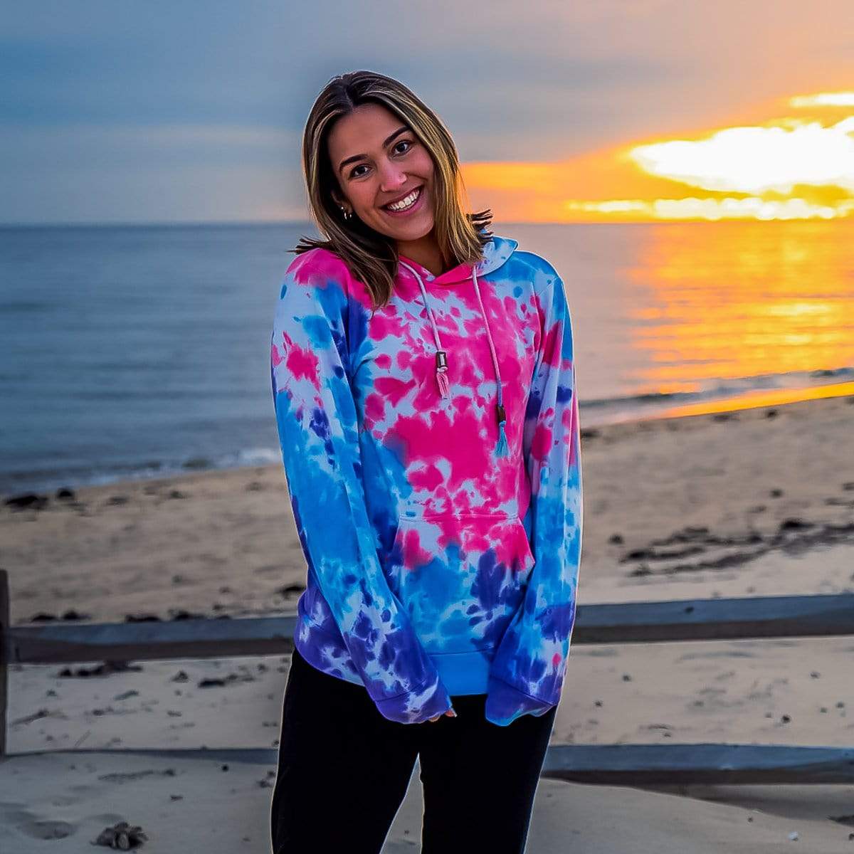 Male Model At The Beach Wearing A Paint Splatter Cloud Blend Hoodie From SLYK