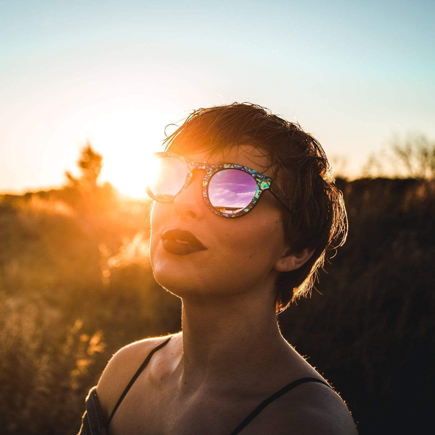 Female Model Wearing Mermaid Wooden Sunglasses With Abalone Seashell and Violet Lenses From SLYK During Sunset