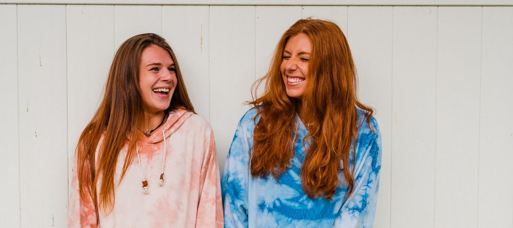 Two laughing models wearing CloudBlend Hoodies in front of a white wall