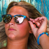 Model Tanning Outside Is Wearing Beachcomber Abalone Wooden Sunglasses With Rose Lenses