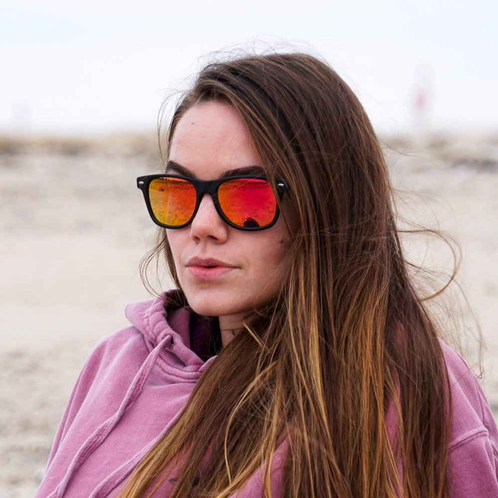 Model Wearing Classic Wooden Sunglasses With Sunset Pink Lenses At The Beach