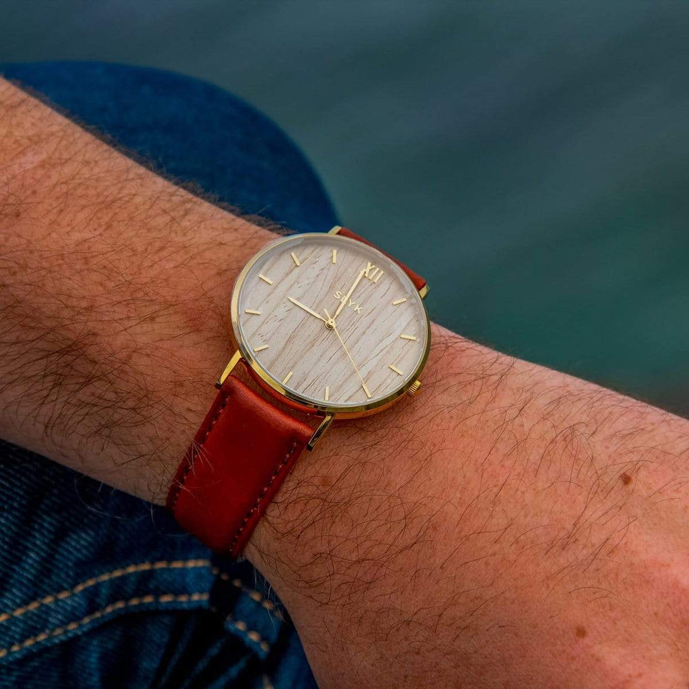 Light Wood Watch In Gold With A Brown Leather Band On A Wrist