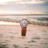 Rose Gold Pink Mother Of Pearl Watch With A Rose Gold Mesh Hanging On A Rope